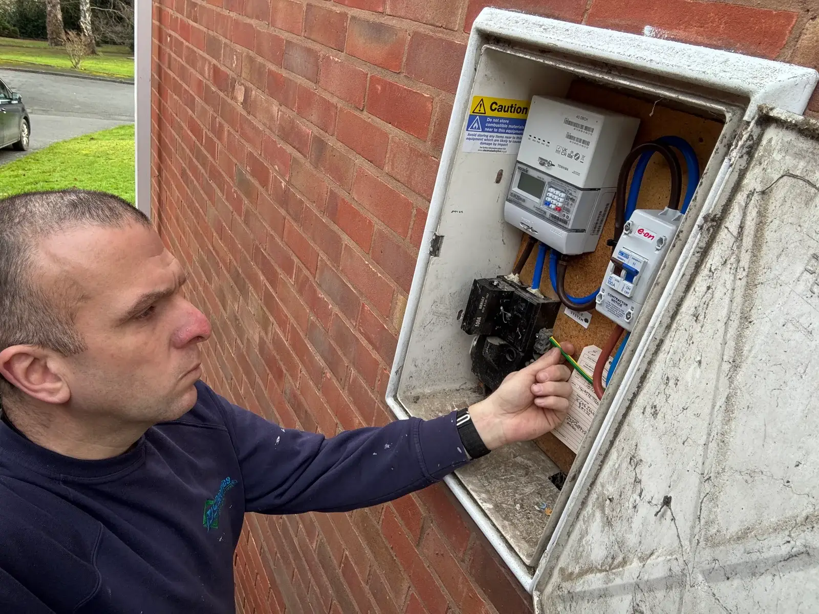 Electrician working on external electrical meter and consumer unit